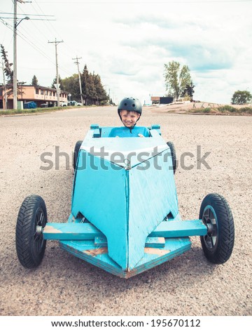 Young boy sitting in a blue homemade soap-box car