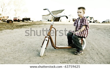 Image of a young boy sitting on a vintage scooter with a straight face.