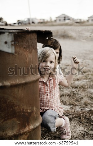Two girls hiding behind a garbage can throwing rocks.
