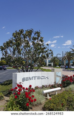 CAMARILLO, CA - APRIL 8, 2015: Hi-Tech company of Semtech front sign and logo with red roses in foreground and magnolia tree, palms and main road to the corporate headquarter office in Camarillo, CA