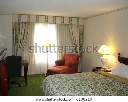 Cozy Bedroom with Queen Bed and Chair next to Window and Lamps