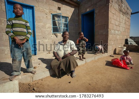 African granny and grandchildren group in a village in Botswana, sitting down in front of the blue door Foto stock © 