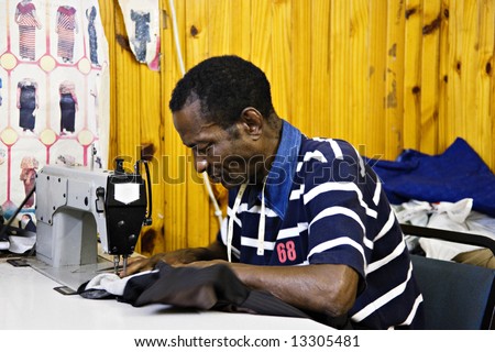 African man sewing in a small tailor shop, industrial sewing machine, African small industry