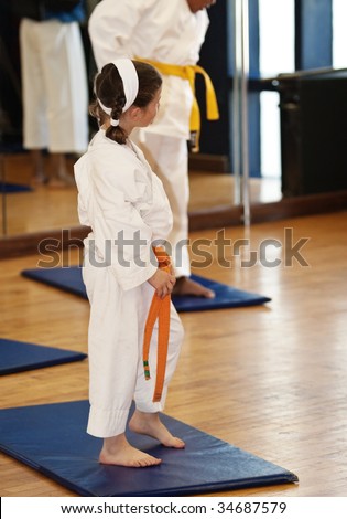 small Caucasian girl at karate practice on the mattress with another African girl