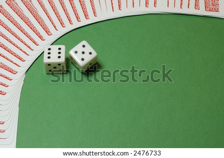 A couple of gambling dices framed  by playing cards on a casino table background