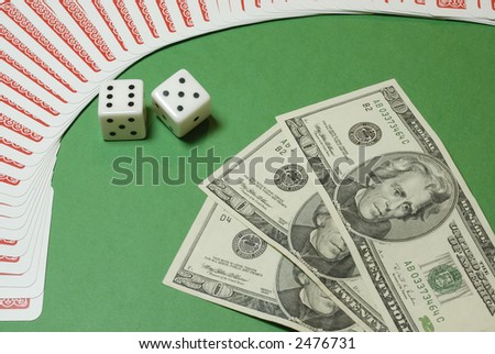 Dollar bills and gambling dices framed by playing cards on a casino table background