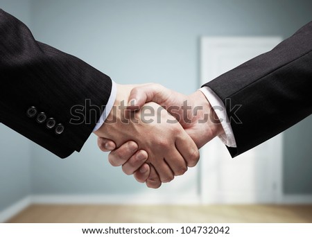 businessmen shaking hands on background of blue room