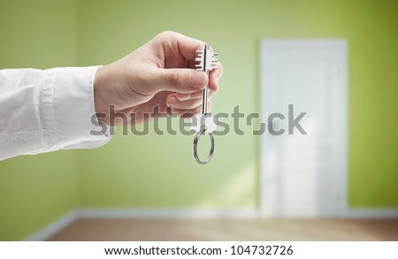key in hand on background of light green room