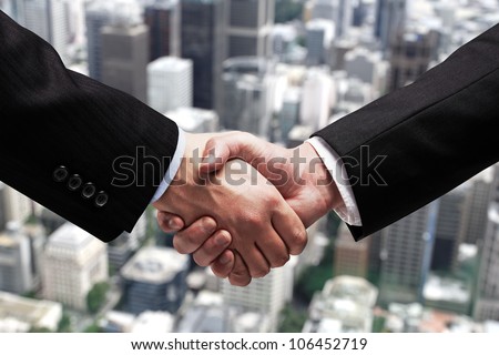 businessmen shaking hands on background of city