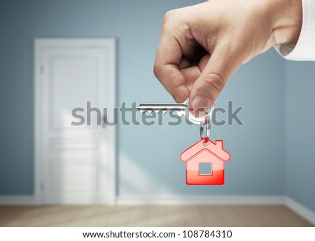 key with key chain in hand against backdrop of rooms