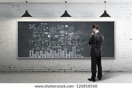 businessman looking at business strategy on blackboard
