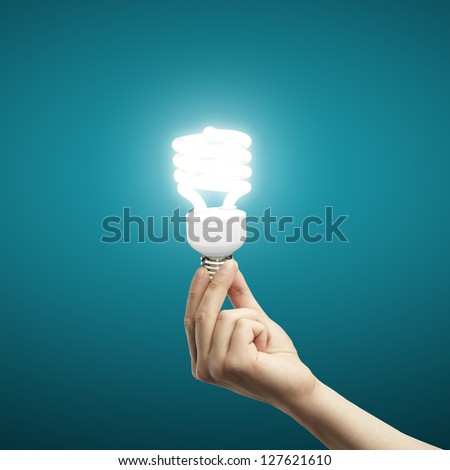 energy saving lamp in hand on blue background