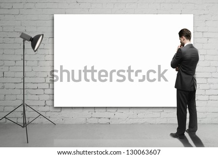 businessman looking at blank poster on wall