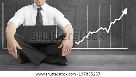 businessman sitting in lotus position and drawing arrow on wall