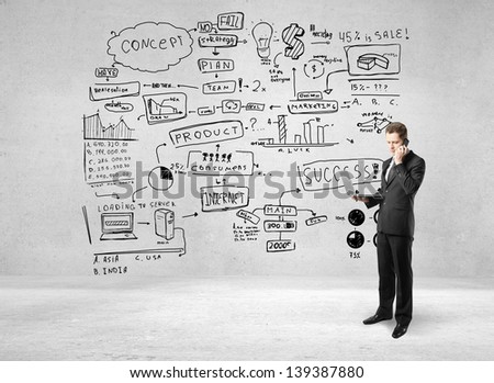 man holding notebook and talking on phone and drawing business strategy on concrete wall