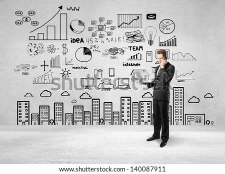 man holding notebook and talking on phone and drawing business strategy on concrete wall