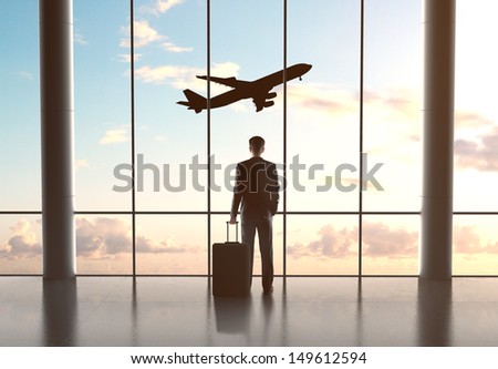 businessman in airport with luggage and looking in airplane