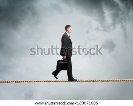 businessman walking on a rope over  clouds