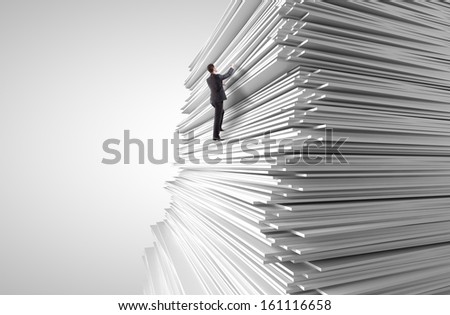 young man climbing up a huge stack of paper
