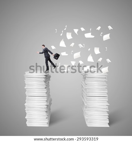 man jumping from top to top of a mountain of papers