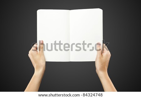 Female hands holding a blank white notebook. On a black background