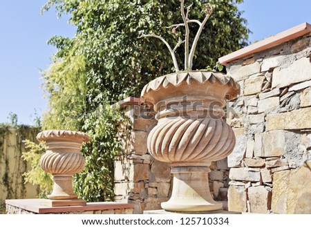 Generic architectural garden landscapefeaturing stone carved plant pots and random local stone masoned wall. Location of shot Rajasthan, India