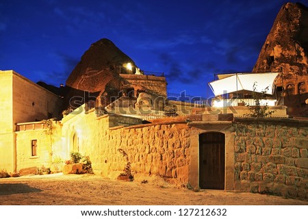 Night scene of Koza Cave Hotel in a Turkish Village under street lights, deep blue sky and scattered stars. Location, Goreme, Turkey, rendered photograph