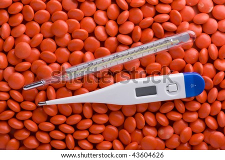 object on red - Medical Tablets and thermometer close up