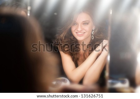 beautiful girl looking through the mirror in dressing room