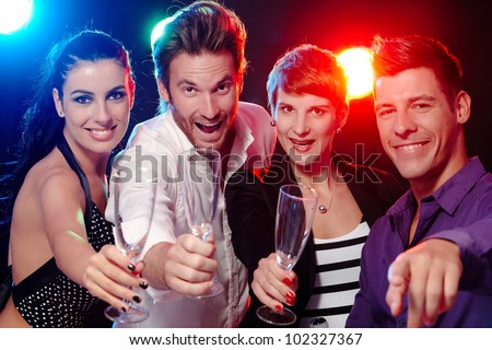 Attractive young people having fun in nightclub, smiling, drinking champagne.