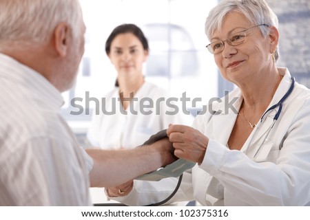 Senior female doctor measuring old man\'s blood pressure.