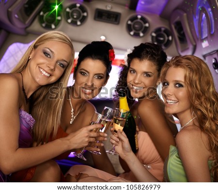 Happy women celebrating in limousine, smiling, looking at camera.