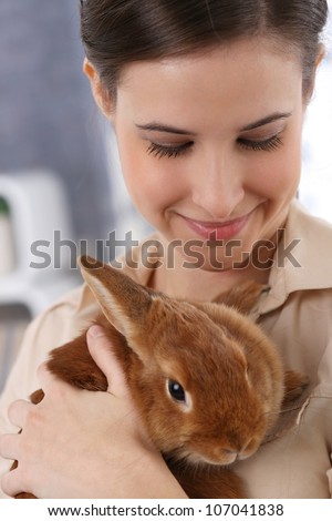 Portrait of happily smiling woman holding cute pet rabbit.