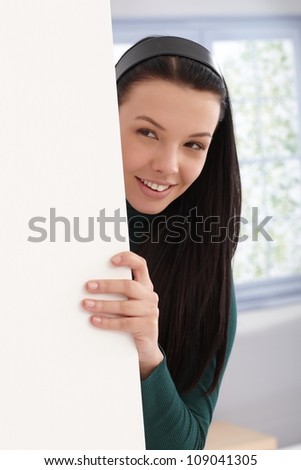 Beautiful smiling girl playing peek-a-boo behind wall.
