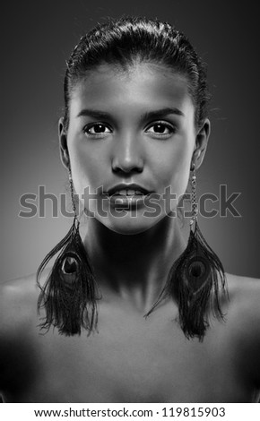 Black-and-white portrait of beautiful young woman with extraordinary earrings.