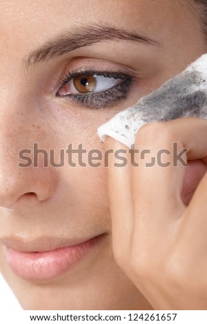 Closeup portrait of young woman removing eye makeup, by cotton pad.