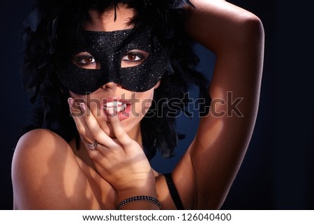 Seductive portrait of attractive woman in posing in black boa and sparkly masquerade.
