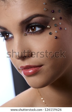 Fancy party makeup with rhinestones on beautiful model, closeup facial portrait.