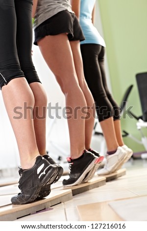 Three females doing calves exercises at the gym. Only legs.