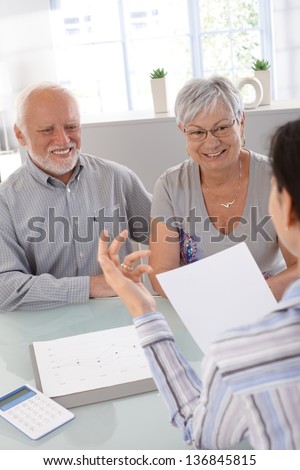 Elderly couple at financial consultation, smiling.