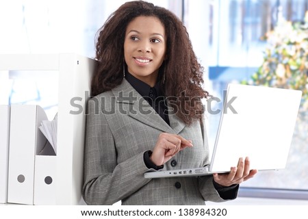 Portrait of beautiful afro-american businesswoman with laptop computer smiling, looking away.