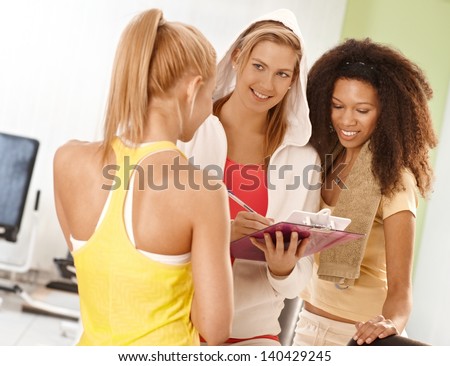 Happy girls talking at the gym with personal trainer.