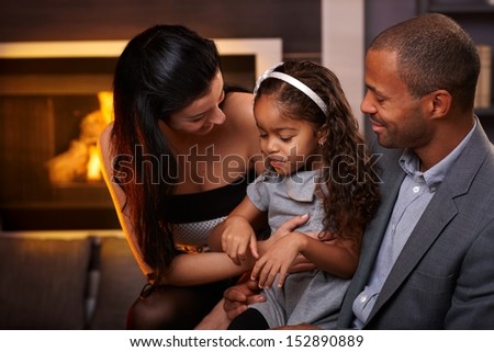 Beautiful loving family sitting in living room by fireplace, smiling.