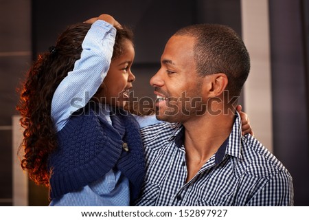 Happy black father and cute little daughter embracing, smiling.