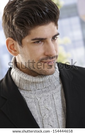 Close-up portrait of casual young man in polo-neck sweater and jacket, looking away.
