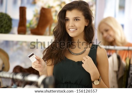 Attractive female paying by credit card at clothes store, smiling happy.