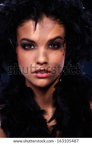 Beauty in black feather boa with intense sexy look and extravagant makeup, stripes of light.