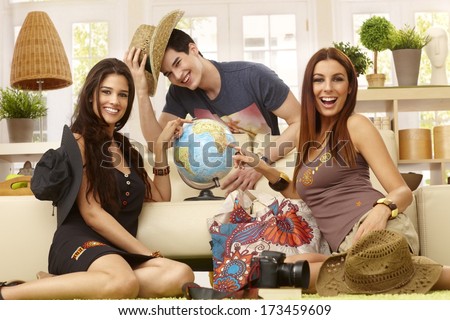 Happy young roommates planning summer holiday, having globe, smiling.