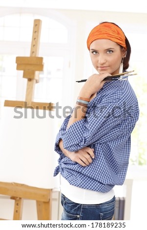 Attractive painter woman posing with brush in hand.