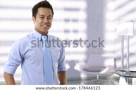 Portrait of happy young asian businessman looking at camera, smiling.